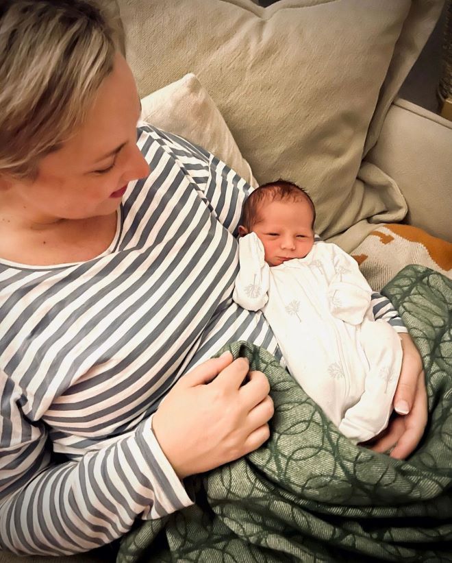 woman wearing ripe maternity breastfeeding top and holding her baby